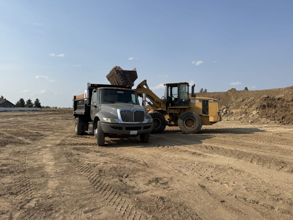 Millsap Supply dump truck being loaded with bulk material by a wheel loader
